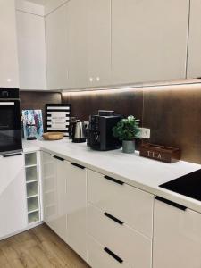 a kitchen with white cabinets and a black microwave at Apartament lovely space in Rzeszów