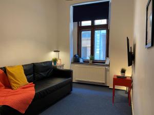 - un salon avec un canapé noir et une fenêtre dans l'établissement Millenium Apartments, à Cracovie