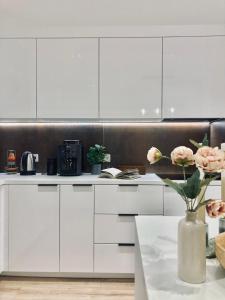 a kitchen with white cabinets and a vase with flowers at Apartament lovely space in Rzeszów