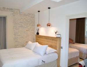 1 dormitorio con 2 camas y pared de ladrillo en Plume Suites, en Fleurey-sur-Ouche