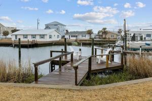 a wooden dock with a boat in the water at Coastal Soul B in Atlantic Beach