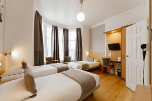 Una habitación de hotel con tres camas y un escritorio. en Star Hotel, en Londres