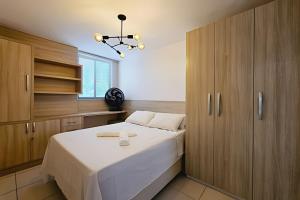 a bedroom with a bed and wooden cabinets at ESPETACULAR 1 dorm com piscina em Manaíra! in Tambaú +18 photos