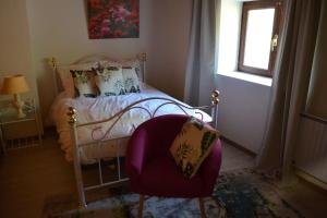1 dormitorio con 1 cama con silla y ventana en maison bourguignonne Le Val Thibault en Buncey