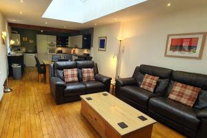 een woonkamer met zwarte lederen meubels en een tafel bij Brew House, Bakewell, with private parking in Bakewell