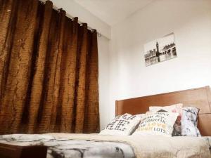 a bedroom with a bed and a brown curtain at RIJHANELS APARTELL in Paradahan