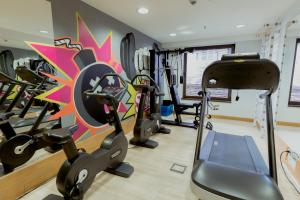 a gym with several tread machines and a colorful wall at Nobel Palace Hotel in Belgrade