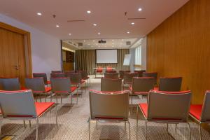 una sala de conferencias con sillas rojas y una pantalla en Nobel Palace Hotel, en Belgrado