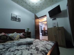 a bedroom with a bed and a flat screen tv at RIJHANELS APARTELL in Paradahan