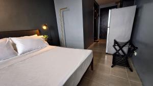 ELUDE Designer Suite Pasig - Prime Location في مانيلا: غرفة نوم بسرير ابيض ولوحة على الحائط