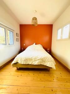 een slaapkamer met een bed met een oranje muur bij Maison au milieu des chevaux in LʼIsle-sur-la-Sorgue