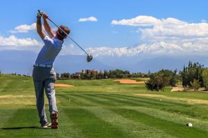 a man swinging a golf club on a golf course at La Ferme de LallaDom in Tameslouht