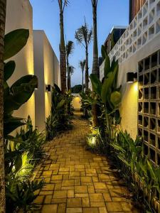 海神廟的住宿－The Hitam Tiny Villa - Stylish Villa in Serene Location 5 Mins to Beach，棕榈树和建筑的砖砌走道