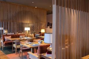 un ristorante con tavoli, sedie e televisore di Soldanella by Hotel Adula a Flims