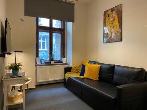 sala de estar con sofá de cuero negro y almohadas amarillas en Millenium Apartments, en Cracovia