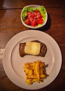 a plate with a sandwich and french fries and a salad at Pousada O Canto do Francês in Soure