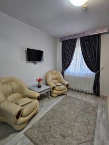 a living room with two chairs and a tv at Hotel Dorobanti in Iaşi