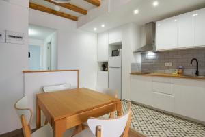 a kitchen with a wooden table and white cabinets at Ol Cute apartment in quiet Olivera st in Barcelona