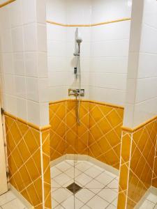 een badkamer met een douche met oranje en witte tegels bij Maison à colombage garage bureau centre village in Francescas