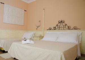 a bedroom with two beds with white sheets and a lamp at Hotel La Rosa dei Venti in Buggerru