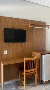 a wooden desk with a television on a wall at Hotel Darcisbel in Cacoal