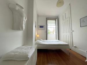 Cette chambre blanche dispose de deux lits et d'une fenêtre. dans l'établissement Hostel Alegria, à Porto