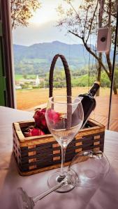 ein Glas Wein neben einem Korb mit Rosen in der Unterkunft Pousada Jardim Encantado - Hospedagem junto a natureza na cidade do Cristo Protetor! in Encantado