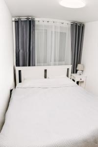 a bedroom with a large white bed with gray curtains at Mano jūra in Palanga