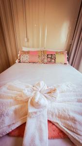ein Bett mit einer weißen Decke und einem Bogen darauf in der Unterkunft Pousada Jardim Encantado - Hospedagem junto a natureza na cidade do Cristo Protetor! in Encantado