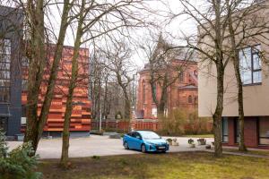a blue car parked in a parking lot next to buildings at Mano jūra in Palanga