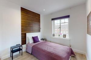 um quarto com uma cama roxa e uma janela em Hampstead 4-bedrooms condo apartment em Londres