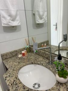 a bathroom counter with a white sink and a mirror at Loft Central in Passo Fundo