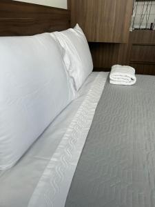 a bed with white sheets and pillows on it at Loft Central in Passo Fundo