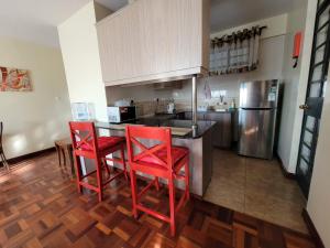 Il comprend une cuisine équipée de chaises rouges et d'un comptoir avec un réfrigérateur. dans l'établissement Wplace - Westlands, à Nairobi