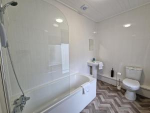 a bathroom with a tub and a toilet and a sink at Oasis 3 Bedroom Home Near Town Centre with garage for bike storage in Dowlais