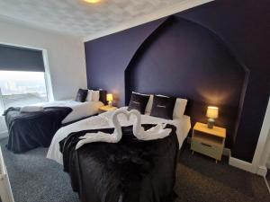 2 camas en una habitación de hotel con paredes púrpuras en Oasis 3 Bedroom Home Near Town Centre with garage for bike storage, en Dowlais