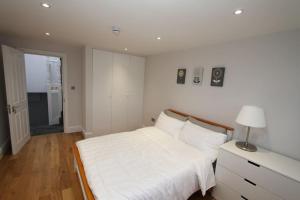 a white bedroom with a large bed and a lamp at Amazing Loft One Bedroom Apartment - E17 Village in London