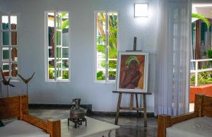 uma sala de estar com um quadro sobre uma mesa e janelas em pousada da sarafina ltda em Salvador