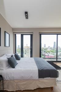a bedroom with a large bed with large windows at InSoho by iPPA in Buenos Aires