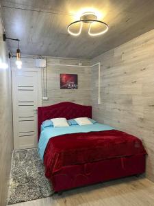 een slaapkamer met een rood bed in een kamer met houten wanden bij Мини отель in Chişinău