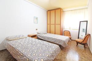 una habitación de hotel con 2 camas y una silla en Global Properties, Piso centrico en Puerto de Sagunto y comodo en Puerto de Sagunto