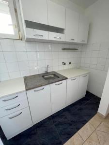 a kitchen with white cabinets and a sink at Apartments Hots in Bar