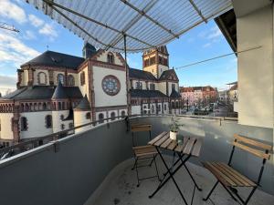 einen Balkon mit Stühlen, einem Tisch und einem Uhrturm in der Unterkunft Zentrales 2-Zi Apartment by Rabe - Kirche - Coffee-Bar in Karlsruhe