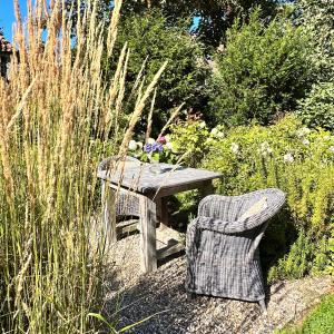 a wooden table and a chair in a garden at Apartments am Wellenreiter in Tating