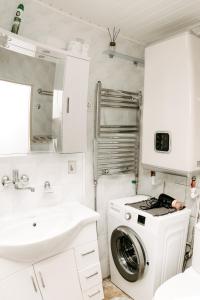 a white bathroom with a washing machine and a sink at Mano jūra in Palanga