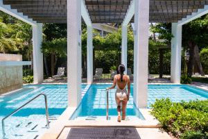 a woman in a bikini walking into a swimming pool at Vista Sol Punta Cana Beach Resort & Spa - All Inclusive in Punta Cana