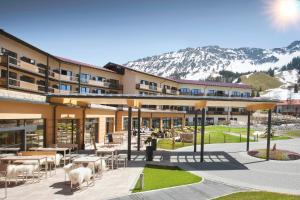 a building with tables and chairs and mountains in the background at Panoramahotel Oberjoch in Bad Hindelang