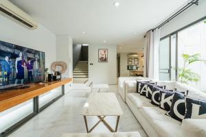 พูลวิลล่ากรุงเทพ في بانغنا: غرفة معيشة مع أريكة بيضاء وتلفزيون