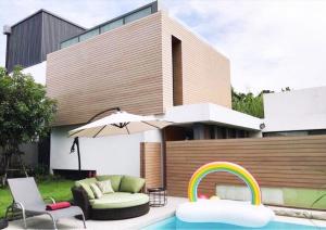 a patio with a couch and an umbrella and a rainbow at พูลวิลล่ากรุงเทพ in Bangna