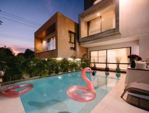 a swimming pool with a pink swan in front of a house at พูลวิลล่ากรุงเทพ in Bangna
